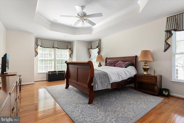 bedroom featuring crown molding, a raised ceiling, light wood finished floors, and baseboards