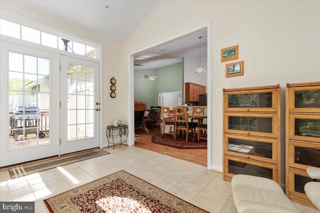 entryway with light tile patterned floors, high vaulted ceiling, and ceiling fan