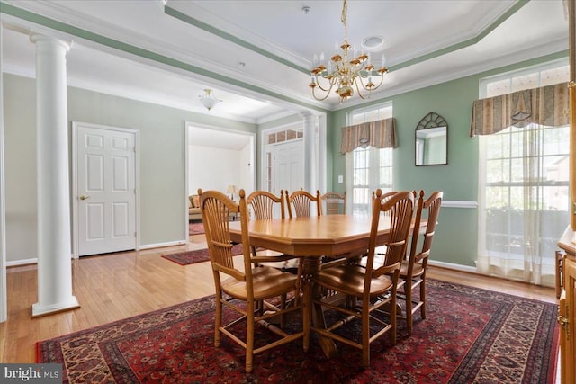 dining area featuring crown molding, ornate columns, a chandelier, and light wood-style flooring