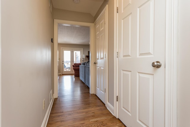 hallway with baseboards, visible vents, and light wood finished floors