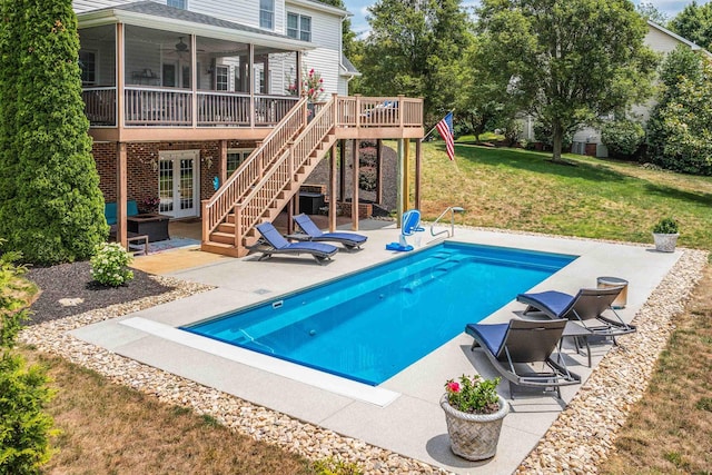 pool with a patio, a yard, french doors, stairway, and a wooden deck