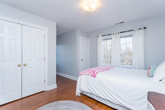 bedroom featuring a closet, visible vents, baseboards, and wood finished floors