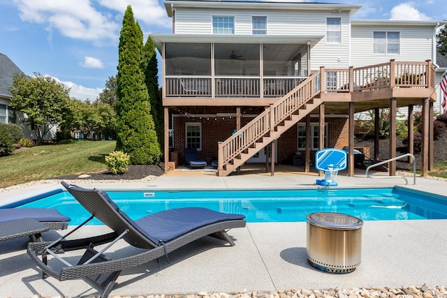 pool featuring a patio, a sunroom, stairs, a yard, and a wooden deck