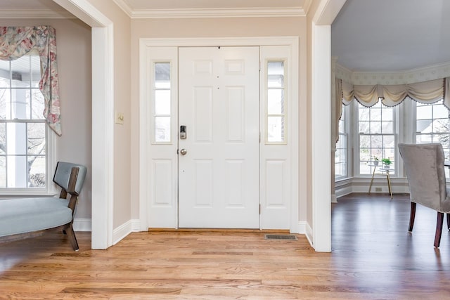 entrance foyer with light wood-style flooring, visible vents, baseboards, and crown molding