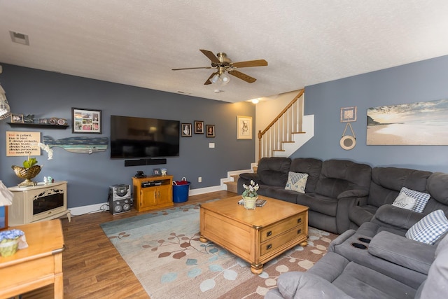 living room featuring visible vents, stairway, ceiling fan, wood finished floors, and baseboards