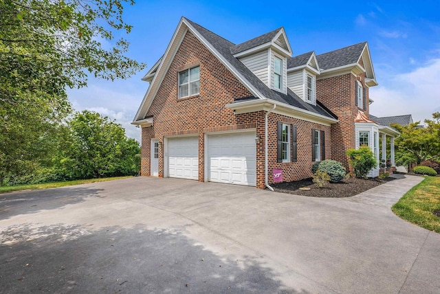 view of side of property featuring a shingled roof, concrete driveway, brick siding, and an attached garage