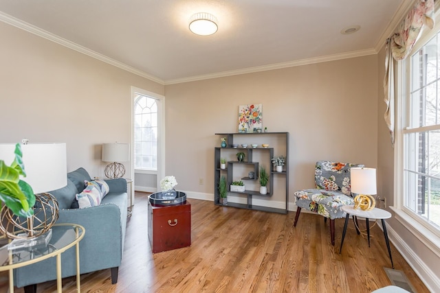 living area with baseboards, wood finished floors, and crown molding