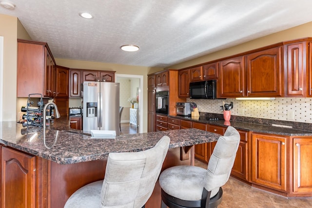 kitchen featuring tasteful backsplash, a sink, black appliances, a peninsula, and a kitchen breakfast bar