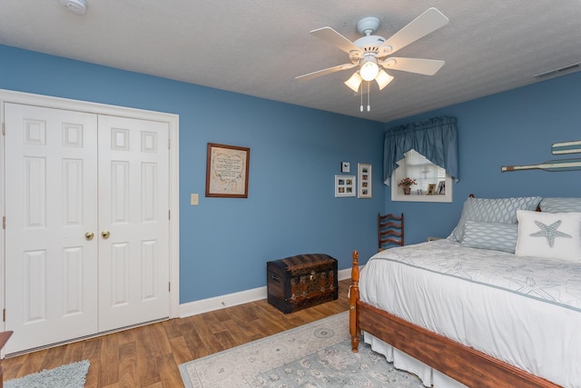 bedroom featuring a textured ceiling, a closet, wood finished floors, and visible vents