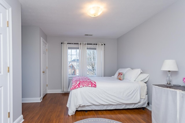 bedroom featuring wood finished floors, visible vents, and baseboards