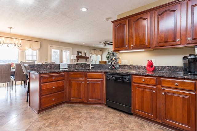 kitchen with a sink, dark stone countertops, dishwasher, a peninsula, and ceiling fan with notable chandelier