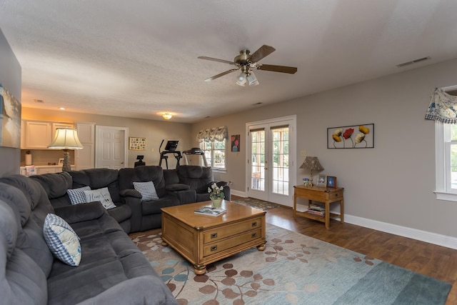 living area featuring a textured ceiling, wood finished floors, visible vents, baseboards, and french doors