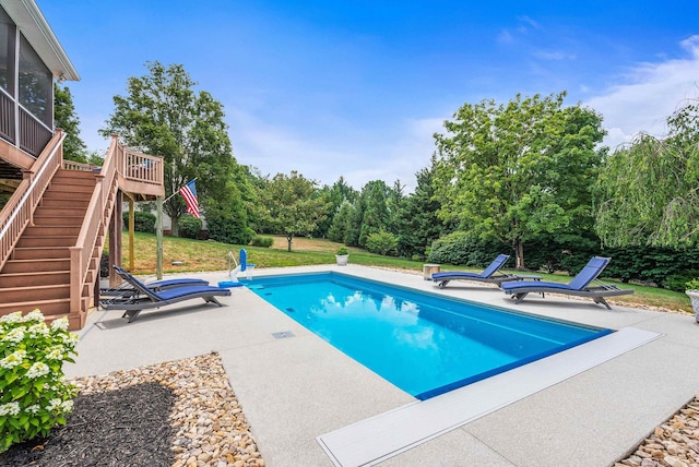 pool featuring a yard, a wooden deck, stairway, and a patio