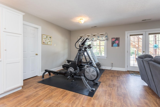 exercise area with french doors, wood finished floors, visible vents, and baseboards