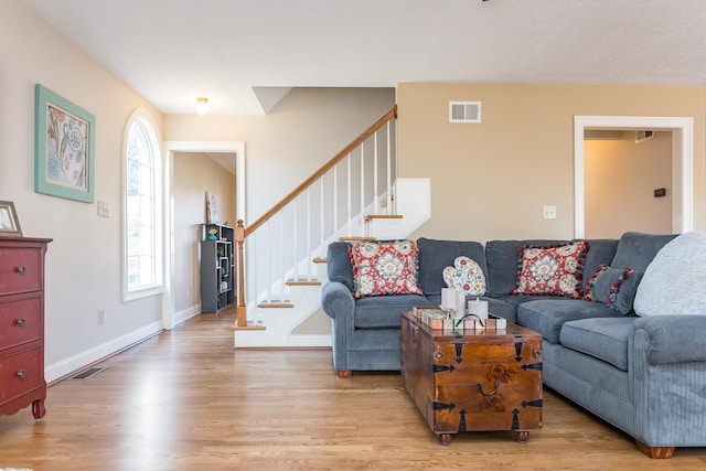 living area with visible vents, stairway, baseboards, and wood finished floors