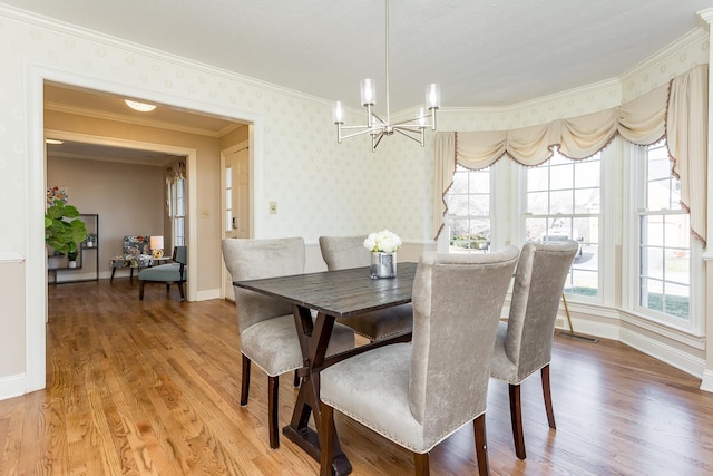 dining area with a notable chandelier, light wood finished floors, baseboards, and wallpapered walls