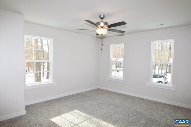 spare room with ceiling fan, plenty of natural light, and light carpet