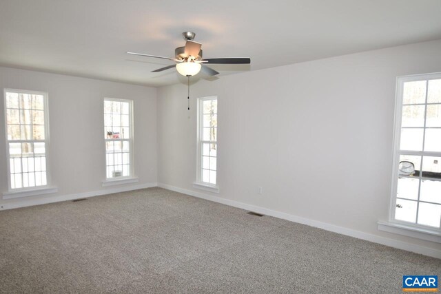 carpeted spare room featuring a wealth of natural light and ceiling fan