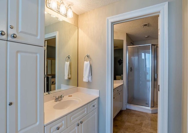 bathroom featuring tile flooring, vanity, a shower with door, and a textured ceiling