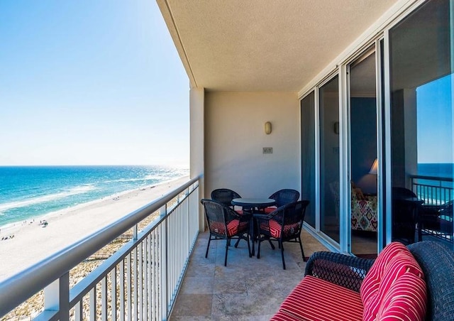 balcony featuring a view of the beach and a water view