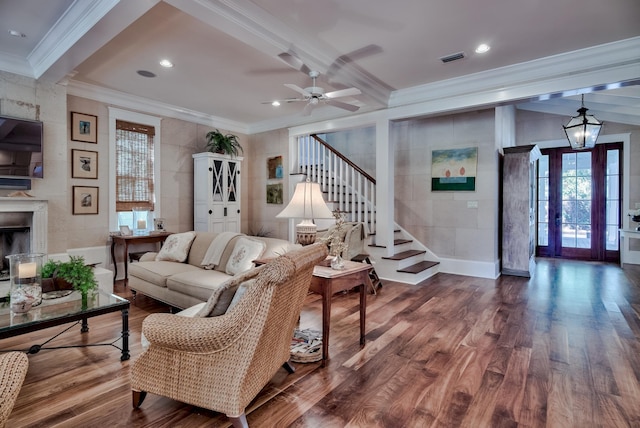 living room featuring ceiling fan with notable chandelier, crown molding, hardwood / wood-style flooring, and tile walls