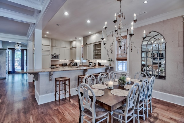 dining room with wood-type flooring, crown molding, sink, and a notable chandelier