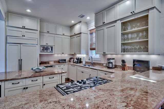 kitchen featuring sink, light stone countertops, white cabinetry, and built in appliances