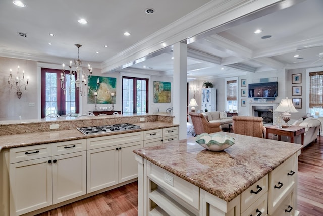 kitchen featuring crown molding, light hardwood / wood-style flooring, stainless steel gas cooktop, and light stone countertops