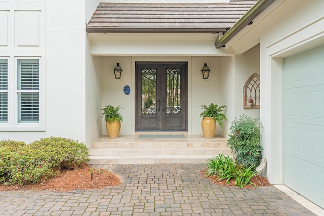 property entrance with french doors, a garage, and stucco siding