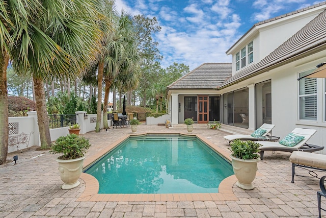 view of pool featuring a patio area, a fenced in pool, fence, and a sunroom