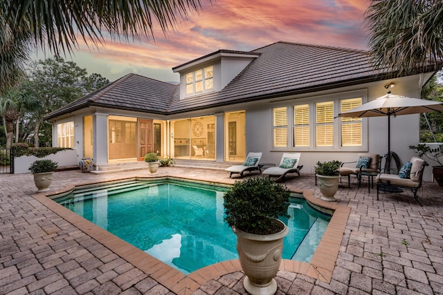 back of property featuring stucco siding, an outdoor pool, and a patio