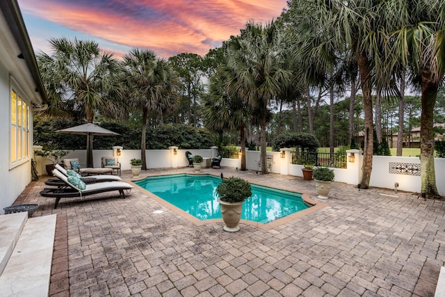 pool at dusk featuring a patio area, a fenced in pool, and fence private yard