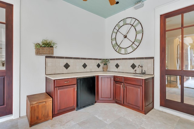 bar featuring refrigerator, a ceiling fan, tasteful backsplash, and a sink