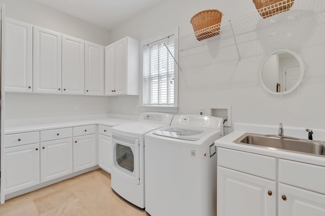 laundry room featuring washing machine and clothes dryer, cabinet space, and a sink