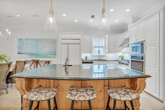 kitchen featuring under cabinet range hood, built in appliances, dark countertops, and ornamental molding