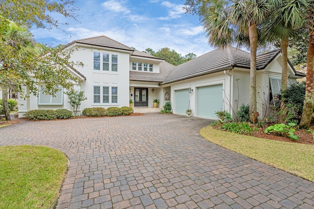 view of front facade with decorative driveway, french doors, a garage, and stucco siding