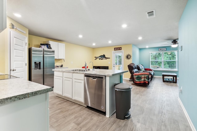 kitchen with sink, stainless steel appliances, white cabinets, and a center island with sink