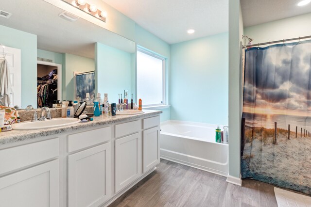 bathroom with wood-type flooring, shower with separate bathtub, and vanity