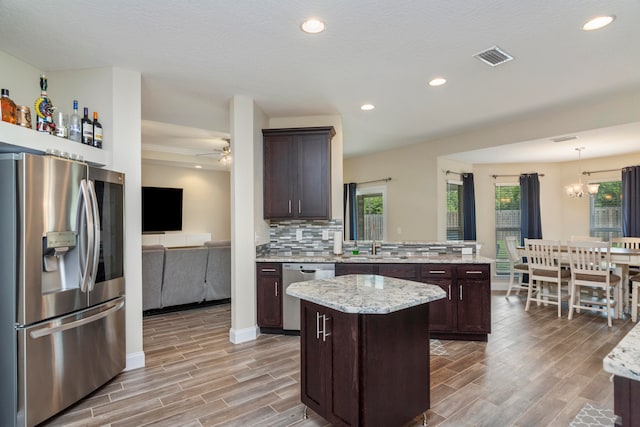 kitchen with stainless steel appliances, a kitchen island, light hardwood / wood-style flooring, and dark brown cabinets