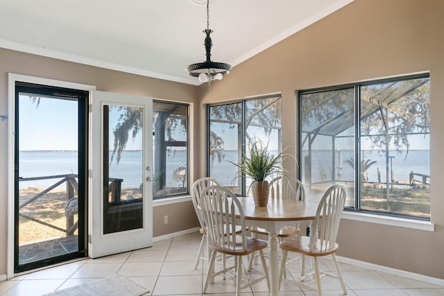 tiled dining room with a water view, crown molding, and vaulted ceiling