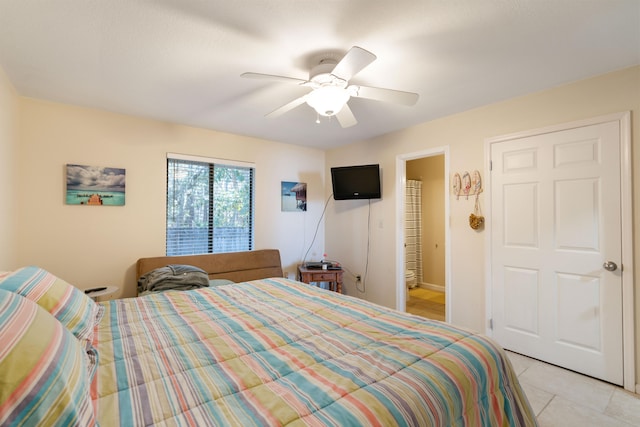 bedroom with ceiling fan, light tile patterned flooring, and connected bathroom