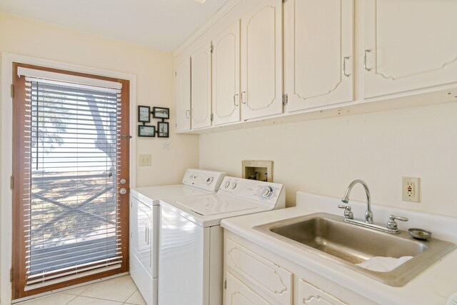 clothes washing area with washer and clothes dryer, sink, light tile patterned floors, and cabinets