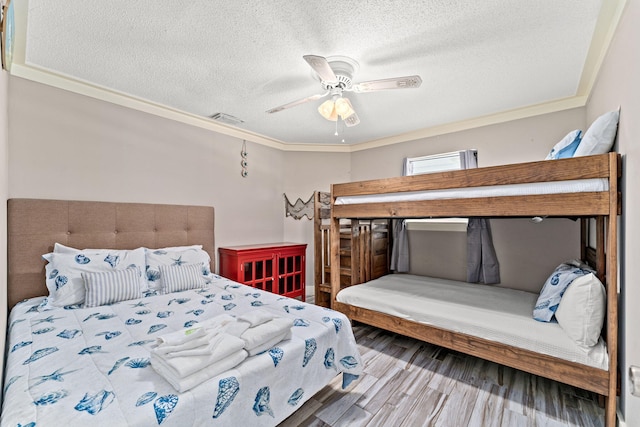 bedroom with a textured ceiling, hardwood / wood-style floors, ceiling fan, and crown molding