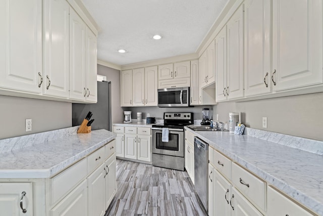 kitchen featuring appliances with stainless steel finishes, light hardwood / wood-style flooring, sink, and white cabinets