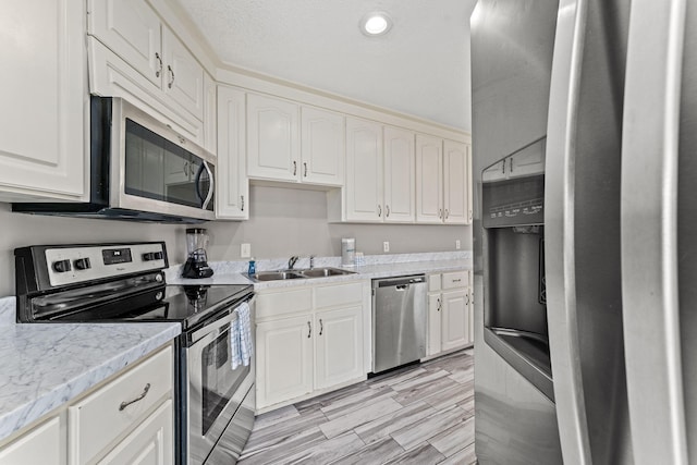 kitchen featuring sink, white cabinetry, stainless steel appliances, and light stone countertops