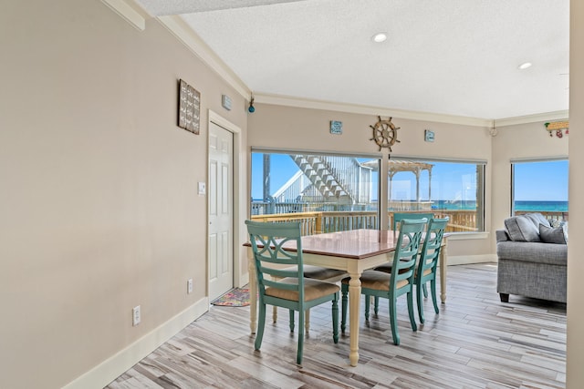 dining room with a healthy amount of sunlight, a textured ceiling, light wood-type flooring, and ornamental molding