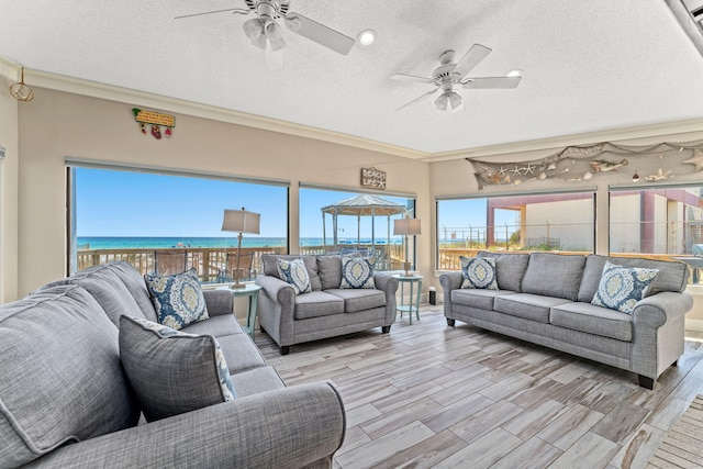 living room with light hardwood / wood-style flooring, ceiling fan, a textured ceiling, and a water view