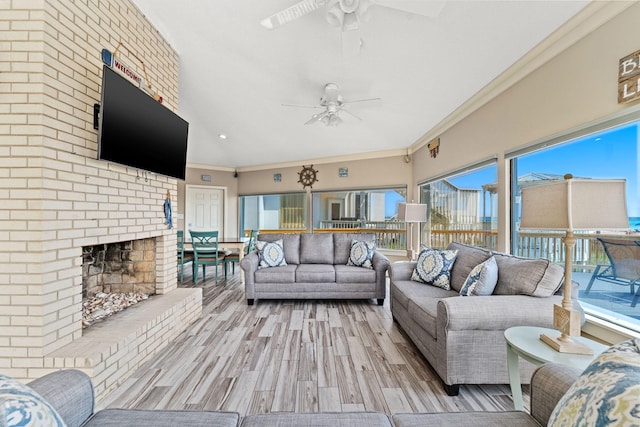 living room with a brick fireplace, ceiling fan, light hardwood / wood-style floors, and ornamental molding