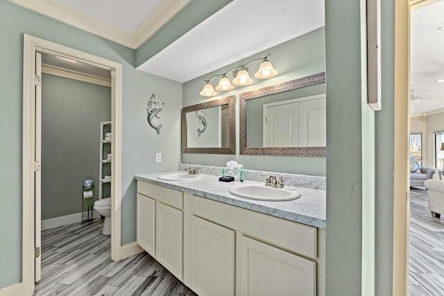 bathroom with dual sinks, crown molding, toilet, and vanity with extensive cabinet space