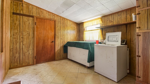 laundry area with wood walls, light tile flooring, and washer / dryer